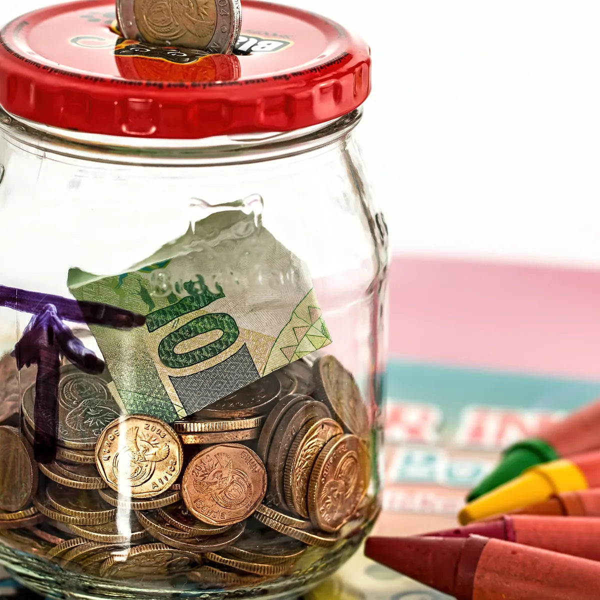 A glass jar holding coins and folded banknotes