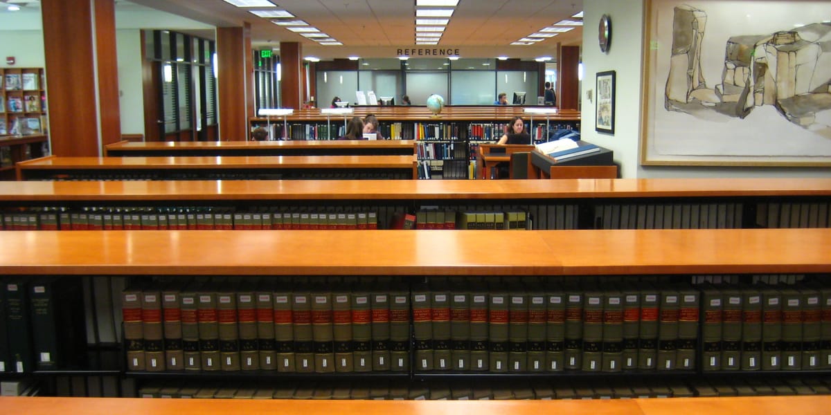 Long rows of bound law reports on low shelves in a library reading area.