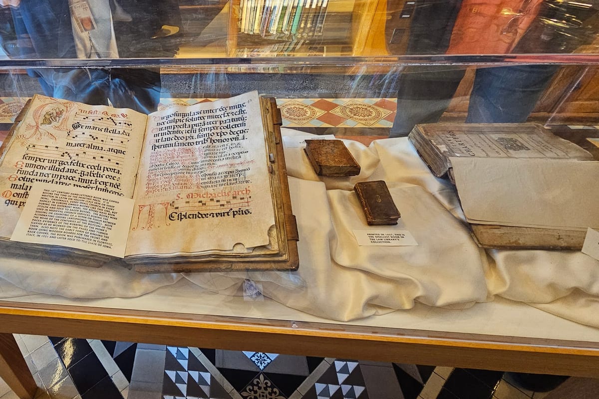 An open early printed law book displayed under glass beside two small bound volumes.
