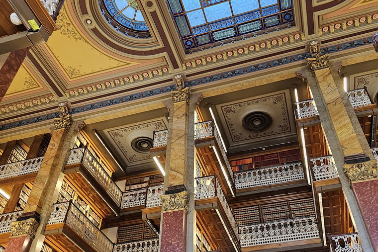 Tiered galleries of bound law reports rising overhead, rail after rail of matching spines.