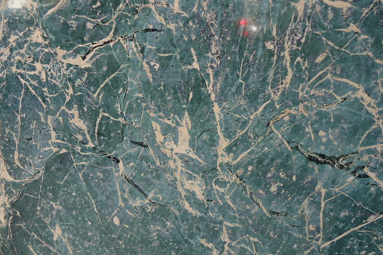 A slab of dark green marble with pale veining running across it.