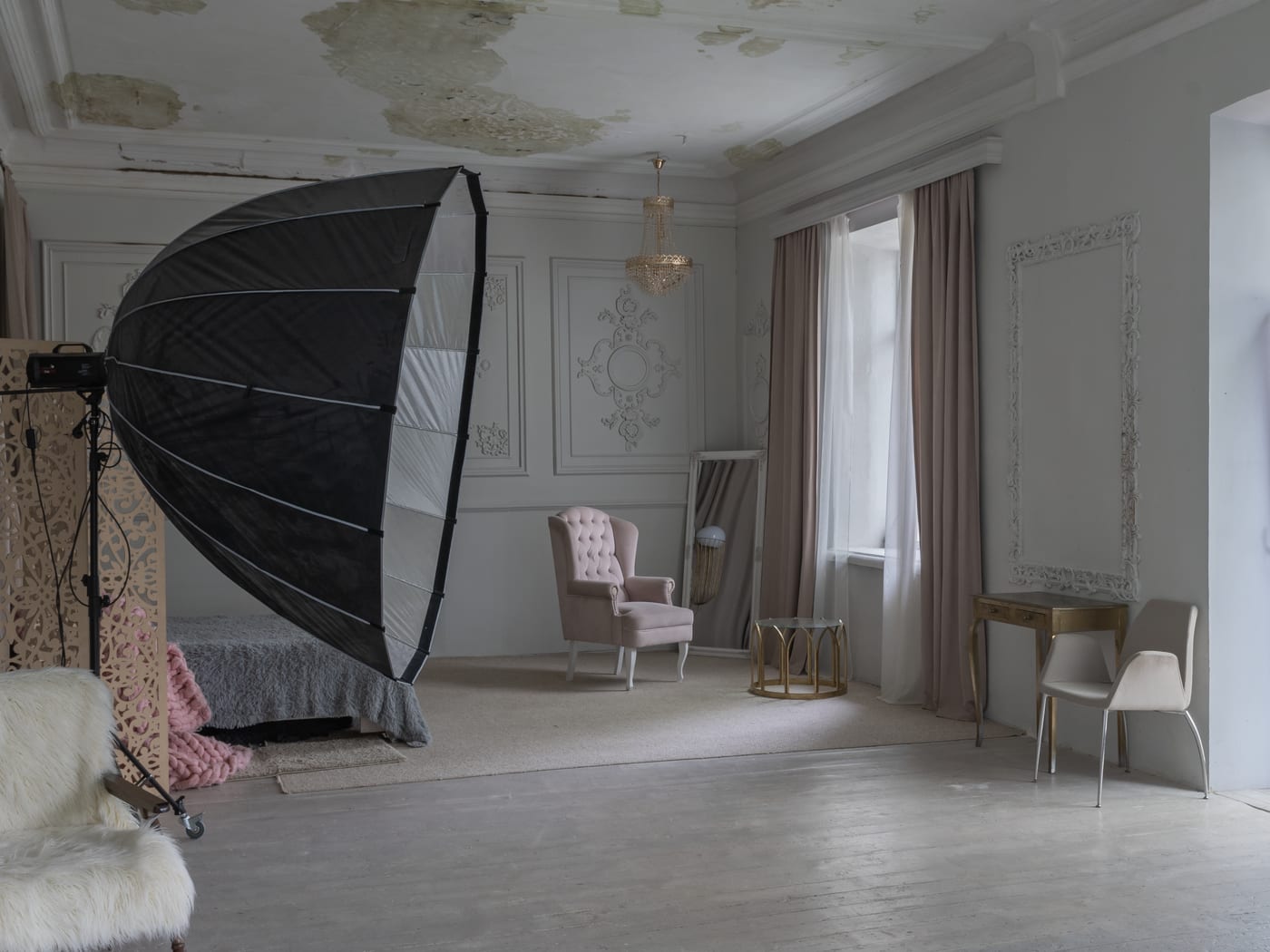 A large octabox on a stand turned towards an armchair in a pale room with moulded walls.