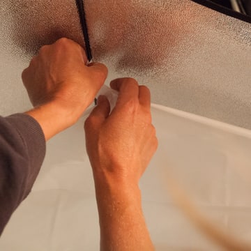 Two hands fastening the diffusion panel onto a softbox frame