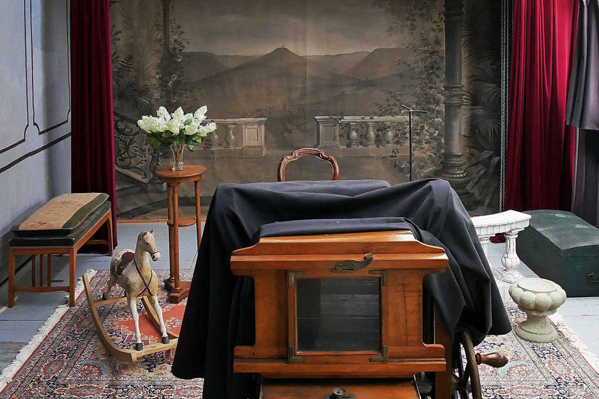 Vintage studio set with a painted backdrop, red drapes and a large-format plate camera