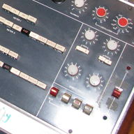 Rows of knobs with red caps beside red buttons.
