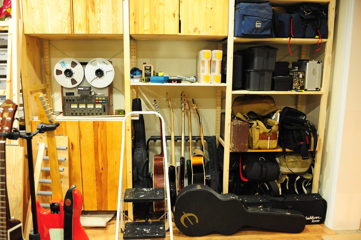 A storage wall of instruments and tape machines along the side of a room.
