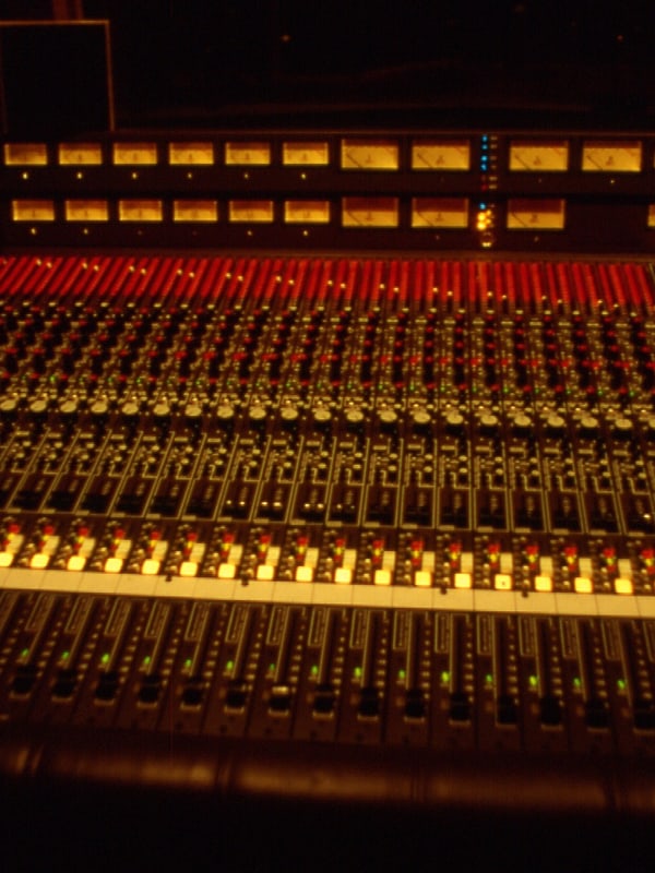 An analogue recording console seen along the fader bank