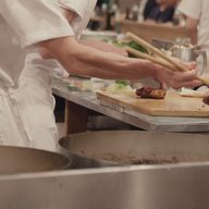 Hands finishing a plate at the pass.