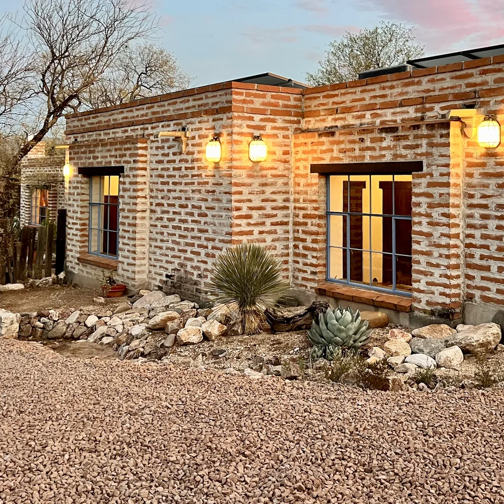 The brick house corner above an agave and gravel courtyard