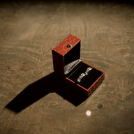 An open red ring box standing on a dark floor, lit from one side.