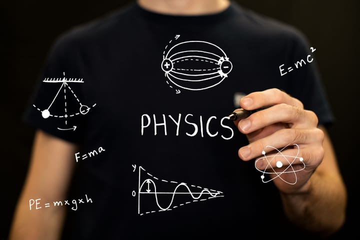 A hand holding a marker over physics notes drawn in white: a pendulum, field lines, an atom, a damped wave and the equation E equals m c squared.