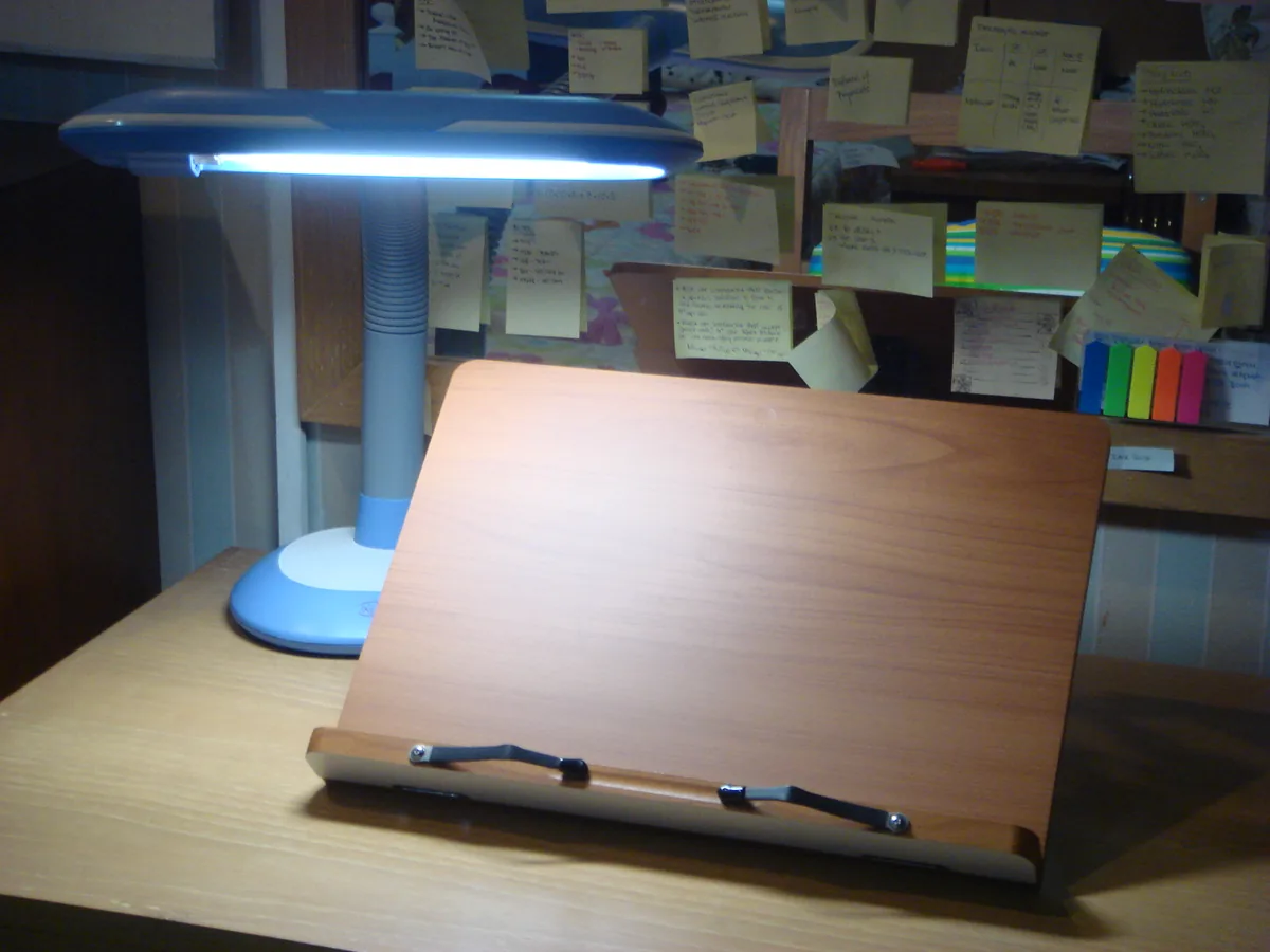 A reading stand and task lamp set up at the study desk
